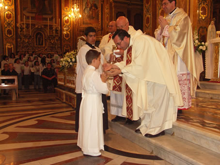 G7 Fr Joe Bajada hands Holy Communion to a relative