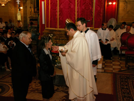 M8 Fr Farrugia's mother receives Holy Communion from her son