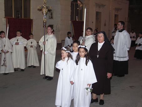 D6 Girls clad in white robes follow tha Blessed Sacrament